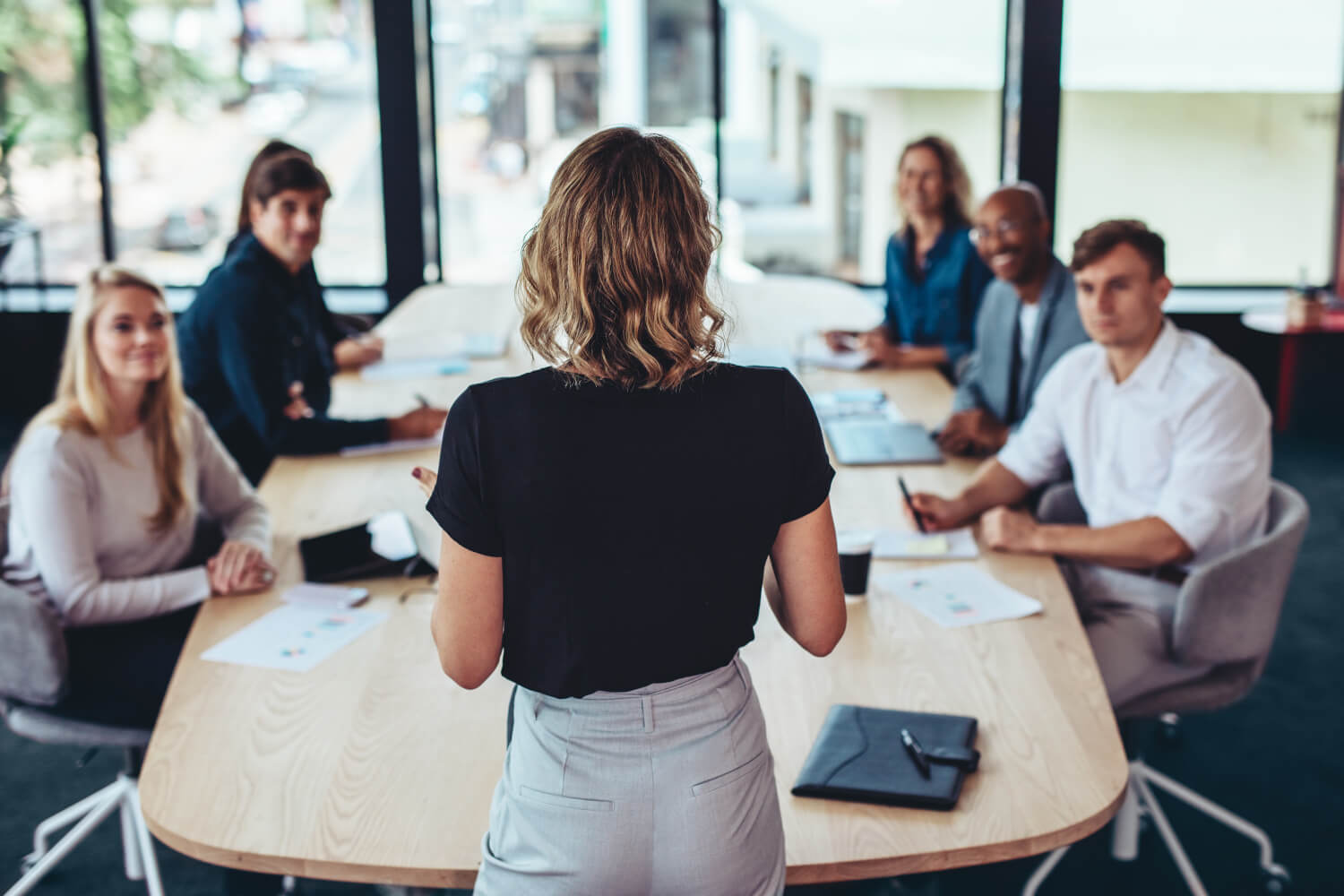 Femme dynamique animant une formation sur les appels d'offres chez MEDIALEX, face à un groupe attentif de professionnels assis autour d'une table.